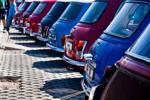 View of several mini classic cars aligned on a row.