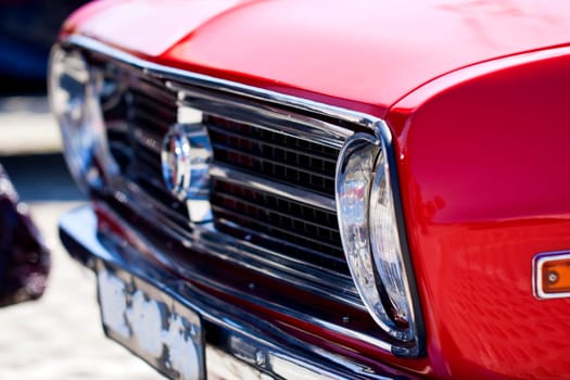 Close view of a classic car from the seventies parked on a park.