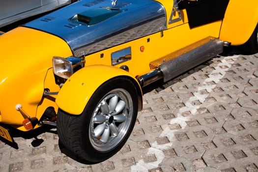 Close view of a weird yellow sports car parked on a park.