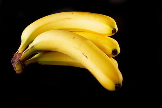 Close up view of a bunch of bananas isolated on a black background.