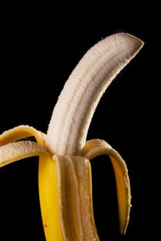 Close up view of peeled banana isolated on a black background.
