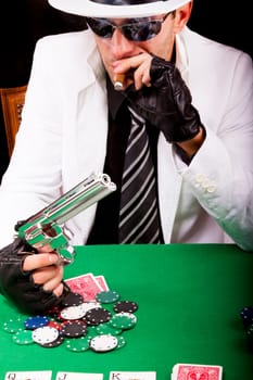 View of a gangster man playing some cards and poker, smoking a Cuban cigar.