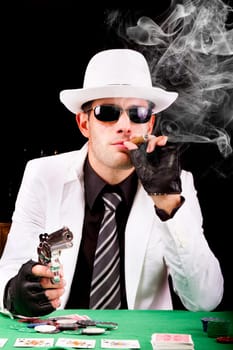 View of a gangster man playing some cards and poker, smoking a Cuban cigar.