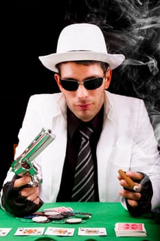 View of a gangster man playing some cards and poker, smoking a Cuban cigar.
