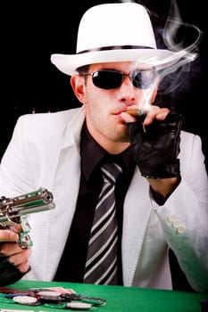 View of a gangster man playing some cards and poker, smoking a Cuban cigar.