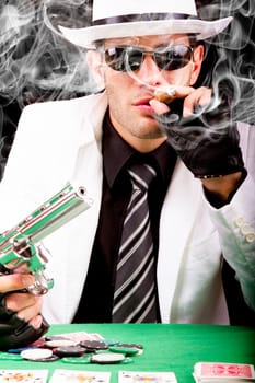 View of a gangster man playing some cards and poker, smoking a Cuban cigar.