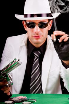 View of a gangster man playing some cards and poker, smoking a Cuban cigar.