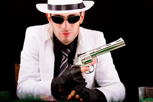 View of a gangster man playing some cards and poker, holding a gun.