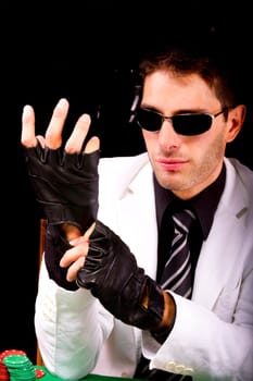 View of a gangster man playing some cards and poker, adjusting the gloves.