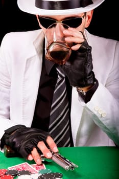 View of a gangster man playing some cards and poker, having a drink.