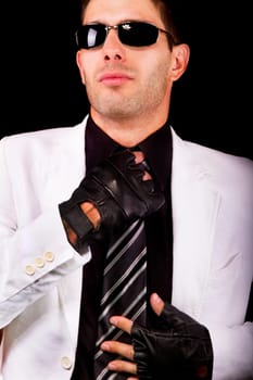 View of a white suit man with gloves, adjusting a tie.