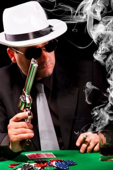 View of a gangster man playing some cards and poker, smoking a Cuban cigar.