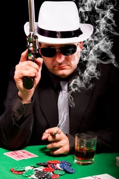 View of a gangster man playing some cards and poker, smoking a Cuban cigar.