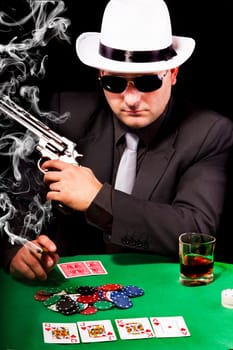View of a gangster man playing some cards and poker, smoking a Cuban cigar.