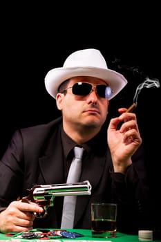 View of a gangster man playing some cards and poker, smoking a Cuban cigar.