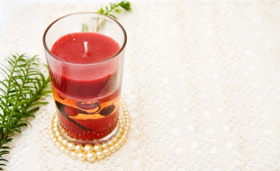 Celebrating Christmas with festive red candle on vintage, handmade lace. Room for your text.