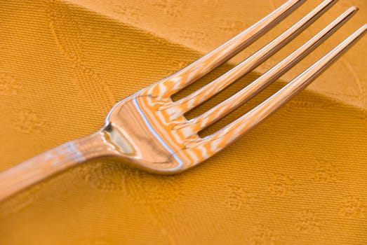 fork on the table in a restaurant with a yellow tablecloth