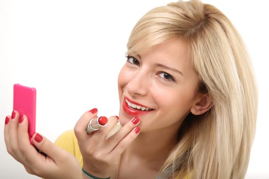 A young smiling blonde doing make up with her small mirror.