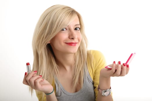 A young blonde showing her make up with lipstick and mirror in hand