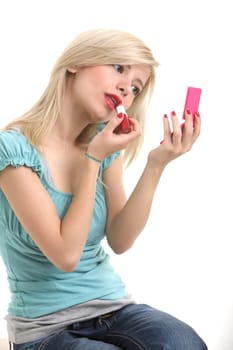 A young blonde doing make up with her small mirror.