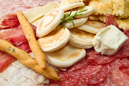 a platter of mixed cured meats, cheeses and fried dumpling