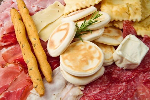 a platter of mixed cured meats, cheeses and fried dumpling