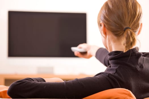 woman with remote control switching channels