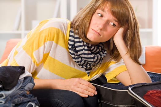 sad woman with luggage packing her clothes