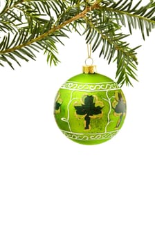 Celebrating Christmas in Ireland with traditional pine tree branch, green hand painted bauble and lucky shamrock. Isolated on white background.