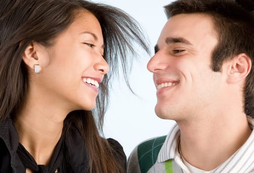 A young couple are laughing while looking at each other.