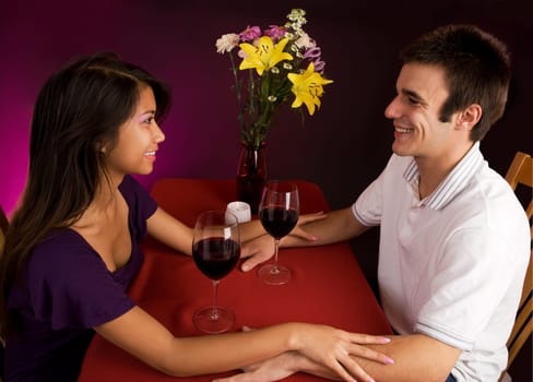 Couple sitting at a table drinking wine and getting close.