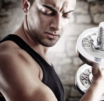Young man doing weights lifting on stone background