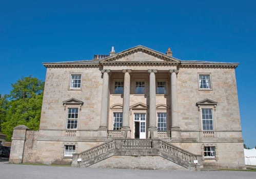 An Eighteenth CenturyStateley Home built in the Palladian Style with ionic pillars under a blue sky