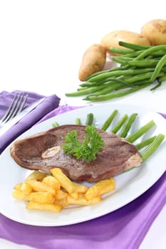 a slice of leg of lamb with green beans and fries