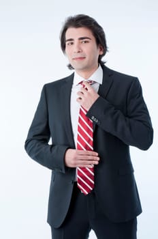 Confident young business man arranging his tie