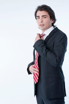 Confident young business man arranging his tie