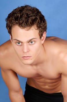 Sexy shirtless young man with blue eyes and brown hair over a blue background
