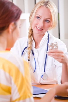 woman doctor holding pills and talking to patient