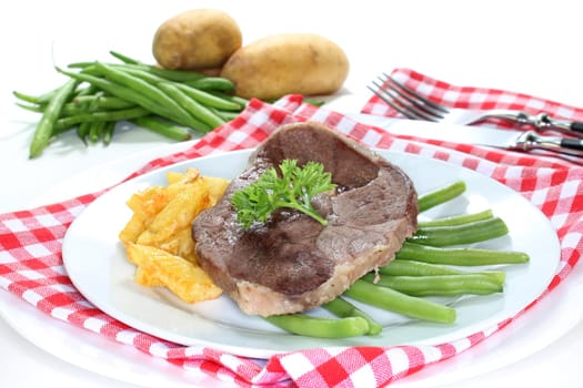 a slice of leg of lamb with green beans and fries