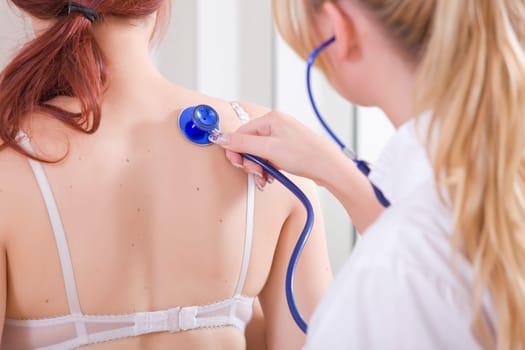 Female Doctor examine a young patient - lungs exam.