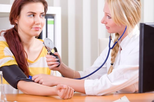 woman doctor measuring blood pressure by patient