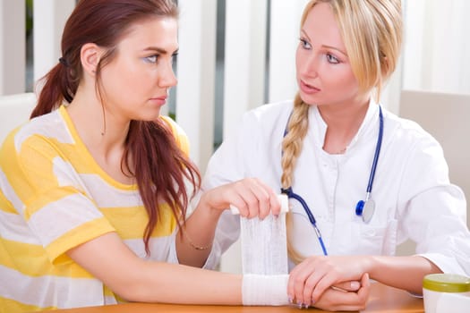 woman doctor applying bandage for the hand to female patient