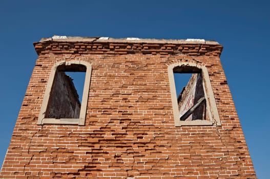 Ruins of a tower with brick walls against a blue clear sky