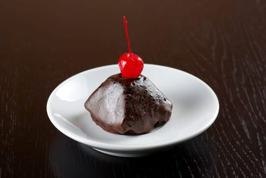fresh baked chocolate cupcake with cherry on a wooden table