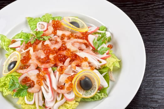 Salad with shrimps, caviar, calamaries, lettuce, lemon and olive