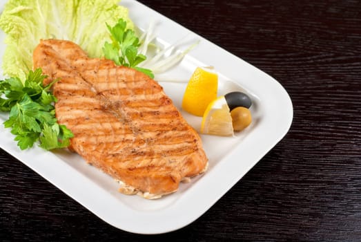 Grilled salmon steak with greens,onion, lemon, lime and olive