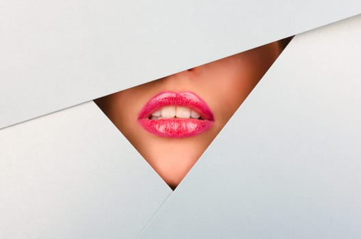 Beautiful female lips closeup behind silver paper background