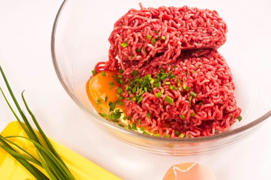 Minced meat with egg and herbs in a glass bowl