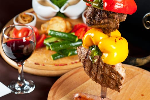 Big tasty roasted meat cuts at skewer on a decorated table