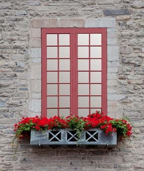 Front view of an old window and a flowerbox on an old stone building.